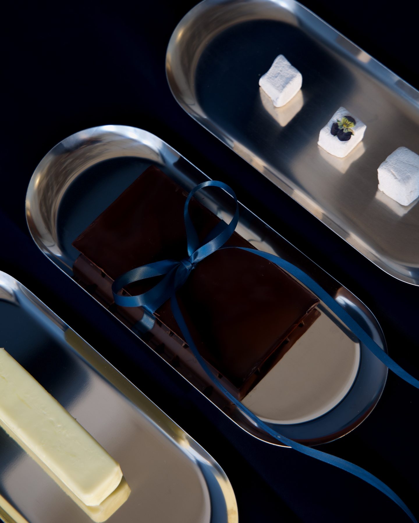Butter, a ribboned chocolate bar and marshmallows on polished steel trays