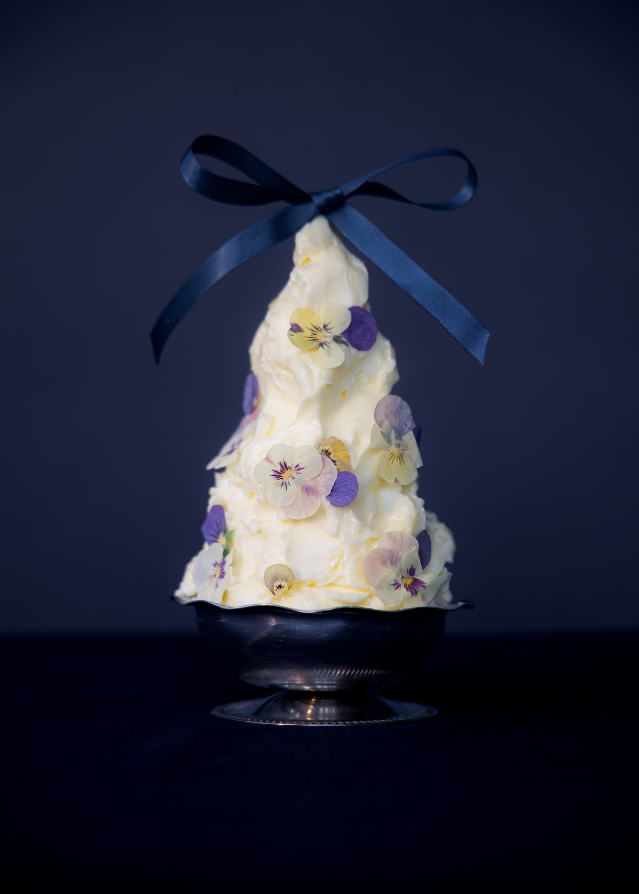A cone of whipped butter studded with pansies, tied with a navy ribbon